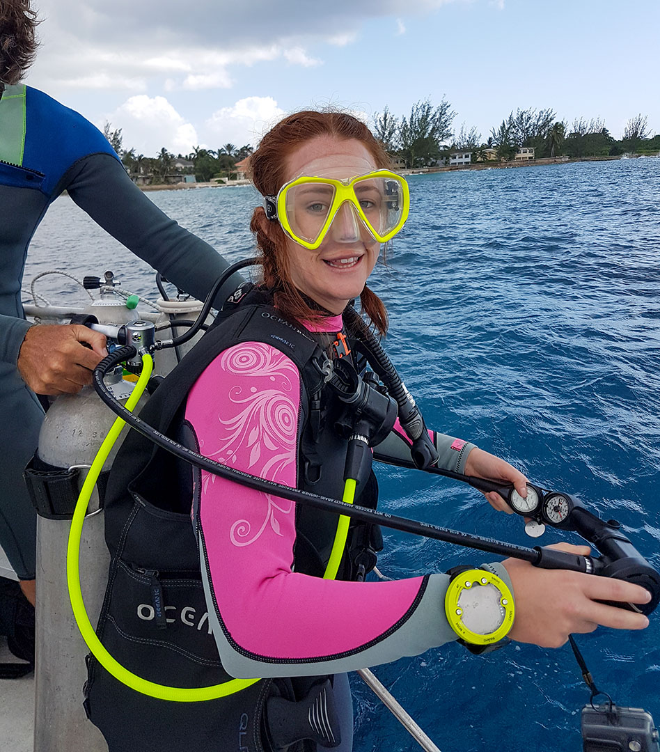 Open water certified female diver ready to jump into the clear warm waters of Grand Cayman you can get your basic scuba course with Rec & Tek SCUBA